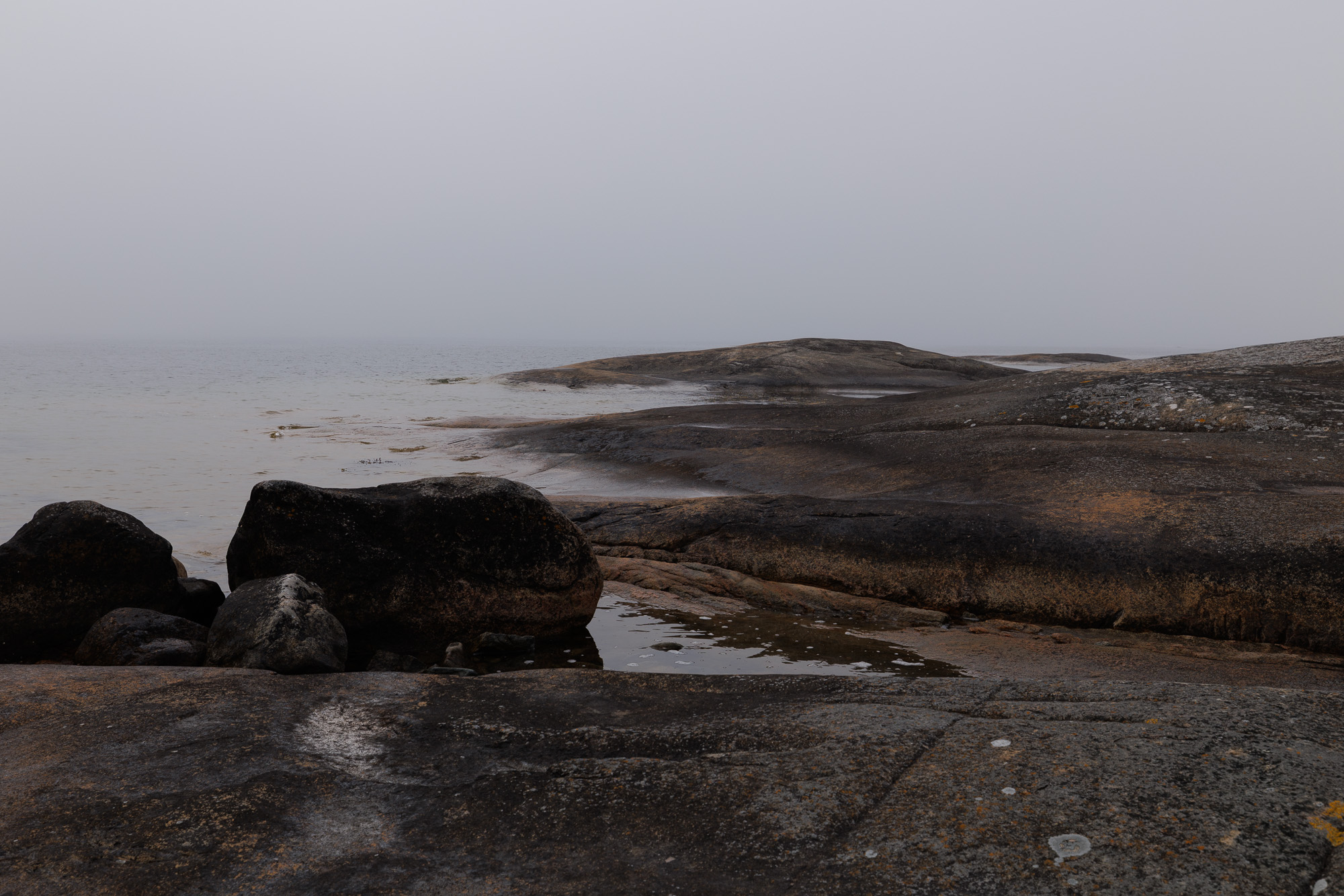 Stora stenblock på släta hällar vid dimmigt hav i Stärnö-Boön Naturreservat