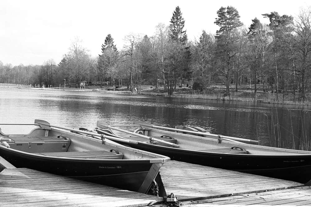 Svartvitt analogt fotografi av båtar vid sjön